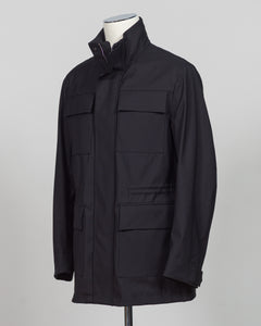A black utility jacket with a high stand-up collar, displayed on a mannequin torso against a neutral gray background.