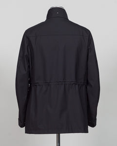 A black long-sleeve jacket with a high collar and a drawstring waist, shown from the back on a mannequin against a light gray background.