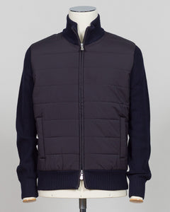 A dark navy blue jacket with a quilted body and ribbed knit sleeves, collar, and hem, displayed on a mannequin against a light gray background. talian wool craftsmanship meets contemporary tailoring in this Gran Sasso sartorial padded jacket. Structured in premium wool with subtle padding for refined warmth, it pairs effortlessly with business wear or elevated casual styling. Gran Sasso Sartorial Padded &nbsp;Wool Jacket / Navy