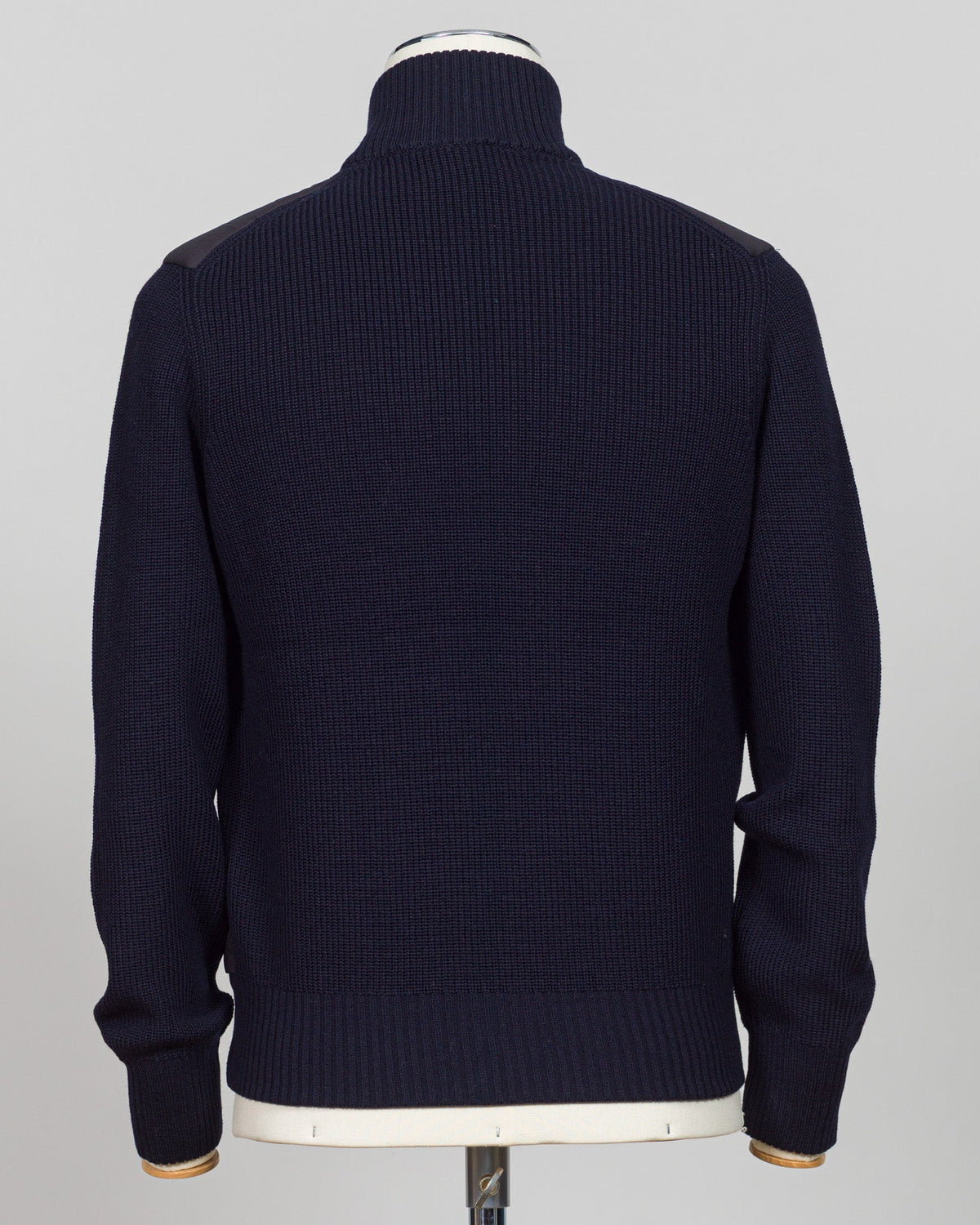 A dark navy blue ribbed knit sweater shown from the back on a mannequin, featuring shoulder patchwork detailing and a mock neck. talian wool craftsmanship meets contemporary tailoring in this Gran Sasso sartorial padded jacket. Structured in premium wool with subtle padding for refined warmth, it pairs effortlessly with business wear or elevated casual styling. Gran Sasso Sartorial Padded &nbsp;Wool Jacket / Navy