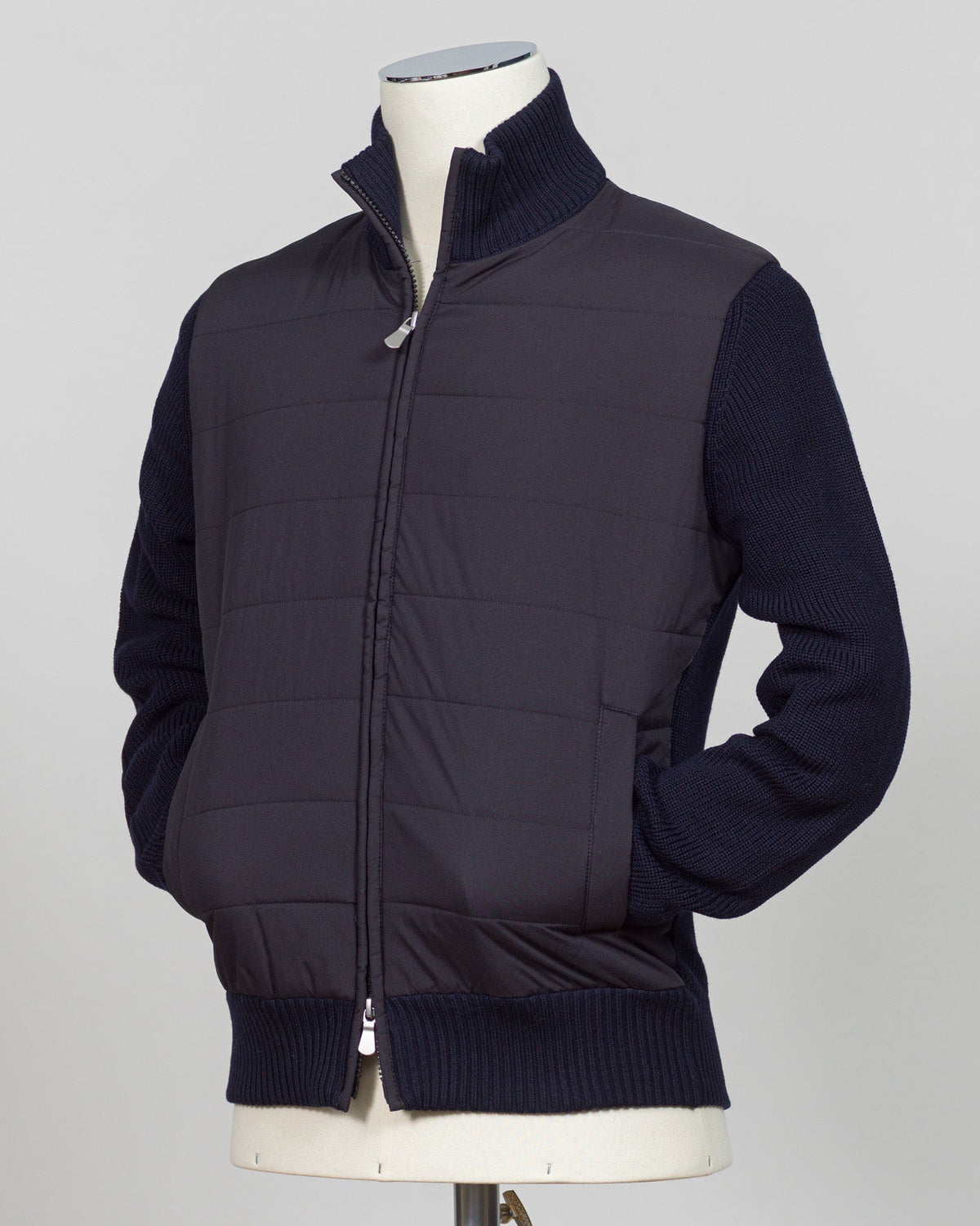 A dark navy blue quilted puffer vest jacket with ribbed knit collar, cuffs, and hem, displayed on a cream mannequin torso against a light gray background. talian wool craftsmanship meets contemporary tailoring in this Gran Sasso sartorial padded jacket. Structured in premium wool with subtle padding for refined warmth, it pairs effortlessly with business wear or elevated casual styling. Gran Sasso Sartorial Padded &nbsp;Wool Jacket / Navy
