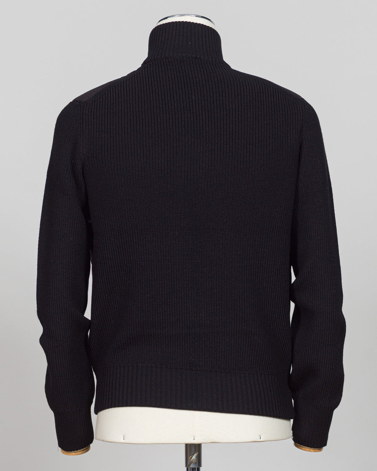 A black ribbed knit turtleneck sweater displayed on a white mannequin torso, viewed from the back against a light gray background. Italian wool craftsmanship meets contemporary tailoring in this Gran Sasso sartorial padded jacket. Structured in premium wool with subtle padding for refined warmth, it pairs effortlessly with business wear or elevated casual styling. Gran Sasso Sartorial Padded &nbsp;Wool Jacket / Black