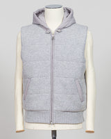 A light gray ribbed knit zip-up vest with a matching gray hood, displayed on a cream-colored mannequin against a light gray background. Lightweight insulation meets refined elegance in this Gran Sasso padded hooded vest. The soft light grey colourway pairs seamlessly with layered knitwear or worn solo over shirts for versatile warmth. Italian craftsmanship ensures a tailored silhouette that bridges casual and smart-casual dressing. Essential for the discerning wardrobe. Gran Sasso Padded Hooded Vest / Light