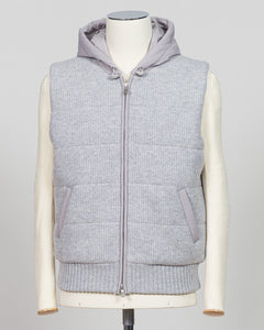 A light gray ribbed knit zip-up vest with a matching gray hood, displayed on a cream-colored mannequin against a light gray background. Lightweight insulation meets refined elegance in this Gran Sasso padded hooded vest. The soft light grey colourway pairs seamlessly with layered knitwear or worn solo over shirts for versatile warmth. Italian craftsmanship ensures a tailored silhouette that bridges casual and smart-casual dressing. Essential for the discerning wardrobe. Gran Sasso Padded Hooded Vest / Light