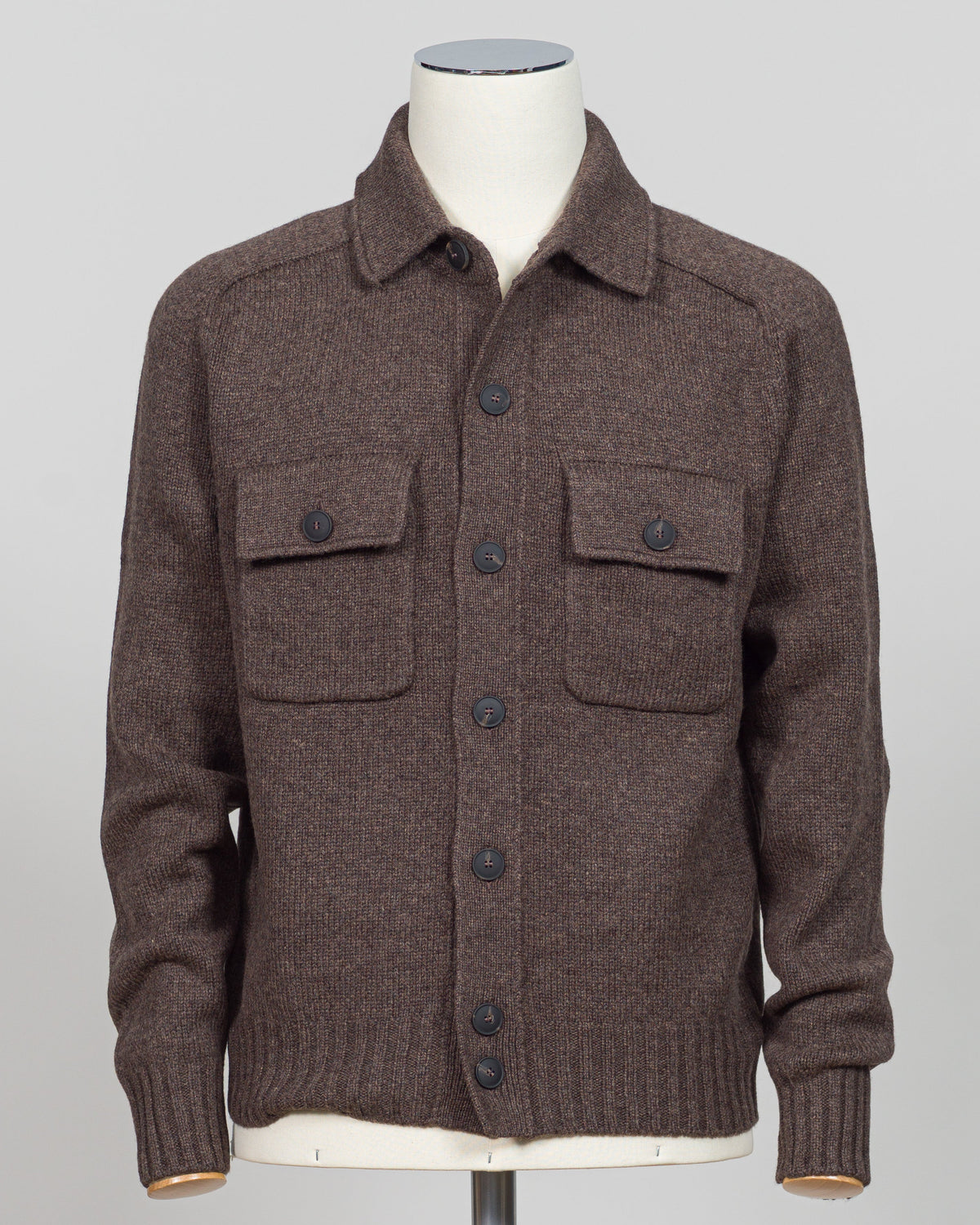 A brown knit button-front cardigan sweater with a collar and two flap chest pockets, displayed on a mannequin torso against a light gray studio background.