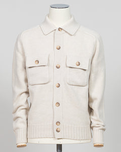 An off-white knit cardigan sweater with brown buttons, displayed on a cream-colored mannequin against a light gray background.