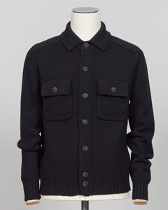 A black knit button-up cardigan sweater with a collar and two chest flap pockets, displayed on a mannequin torso against a light gray background.