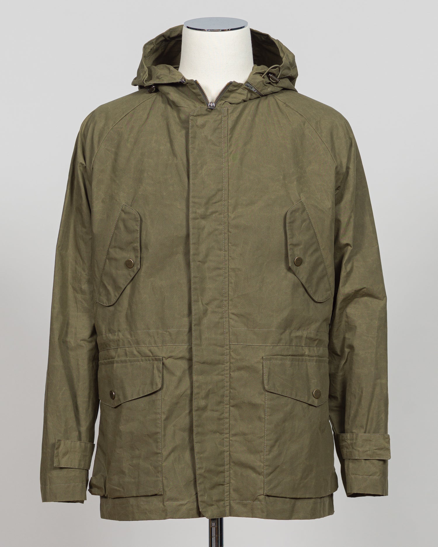A timeless waxed cotton short parka built for versatile layering and unpredictable weather. The water-resistant finish and structured silhouette offer refined protection without bulk, while the compact length ensures easy movement and pairs seamlessly with tailored pieces. Durable construction and a refined aesthetic make it a wardrobe essential for the discerning gentleman.