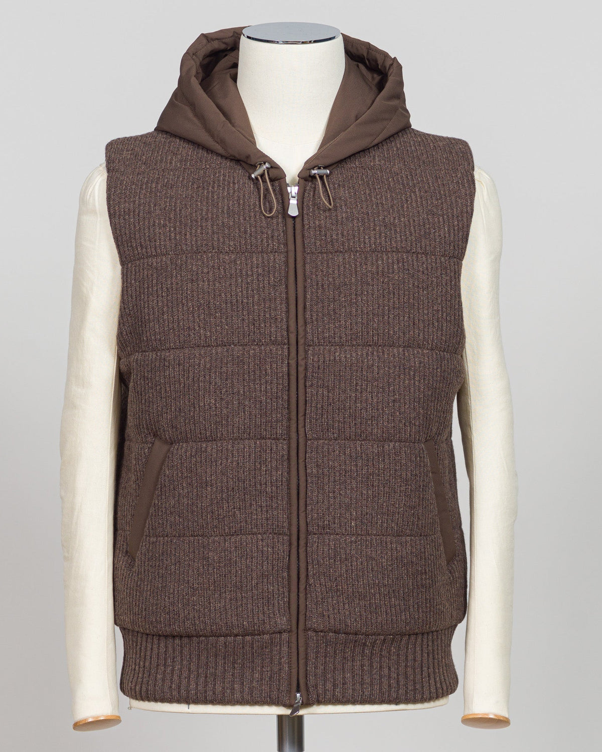 Lightweight padded hooded vest in rich brown, crafted by Italian luxury knitwear specialist Gran Sasso. Designed for layering over fine knits and tailored pieces, this vest offers warmth without bulk. The structured silhouette and refined proportions suit both casual and smart-casual styling. Perfect for transitional seasons and travel. Gran Sasso Padded Hooded Vest / Brown