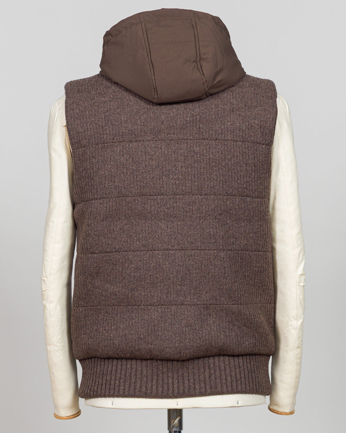 Lightweight padded hooded vest in rich brown, crafted by Italian luxury knitwear specialist Gran Sasso. Designed for layering over fine knits and tailored pieces, this vest offers warmth without bulk. The structured silhouette and refined proportions suit both casual and smart-casual styling. Perfect for transitional seasons and travel. Gran Sasso Padded Hooded Vest / Brown