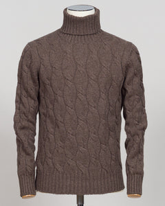 A brown cable-knit turtleneck sweater displayed on a mannequin torso against a light gray background.  Italian wool cable knit roll neck in rich brown. Classic construction with texture and warmth, cut for refined layering under tailored jackets or worn as a standalone piece. Gran Sasso delivers understated luxury in heritage knitwear. Gran Sasso Cable Roll Neck Knit / Brown