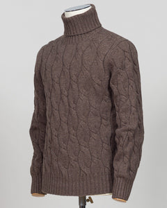 A brown cable-knit turtleneck sweater displayed on a mannequin torso against a light gray background.  Italian wool cable knit roll neck in rich brown. Classic construction with texture and warmth, cut for refined layering under tailored jackets or worn as a standalone piece. Gran Sasso delivers understated luxury in heritage knitwear. Gran Sasso Cable Roll Neck Knit / Brown