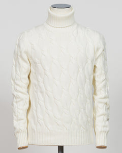 An off-white cable-knit turtleneck sweater displayed on a mannequin torso against a light gray background.  Italian craftsmanship meets timeless elegance in this Gran Sasso cable knit roll neck. Pure white wool construction delivers warmth and refined texture, while the classic silhouette transitions effortlessly from casual to smart-casual layering. A versatile essential for the considered wardrobe. Gran Sasso Cable Roll Neck Knit / White