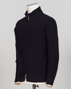 A black ribbed knit zip-up sweater displayed on a cream mannequin torso against a light gray studio background. Italian craftsmanship meets weatherproof functionality in this Gran Sasso rain wool hoodie. Constructed from premium wool blended with water-resistant properties, it delivers warmth and protection without bulk. The relaxed fit and classic black colorway make it a versatile layering essential for unpredictable Nordic weather. Finished with refined detailing befitting Gran Sasso's heritage of fine k
