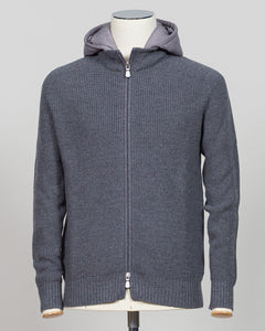 A dark gray ribbed knit zip-up hoodie with a lighter gray hood lining, displayed on a mannequin torso against a neutral light gray Water-repellent merino wool hoodie in warm grey. Engineered for layering and everyday wear, this Gran Sasso piece combines breathable warmth with practical weather resistance. Perfect for transitional seasons and active lifestyles. Gran Sasso Rain Wool Hoodie / Greybackground.