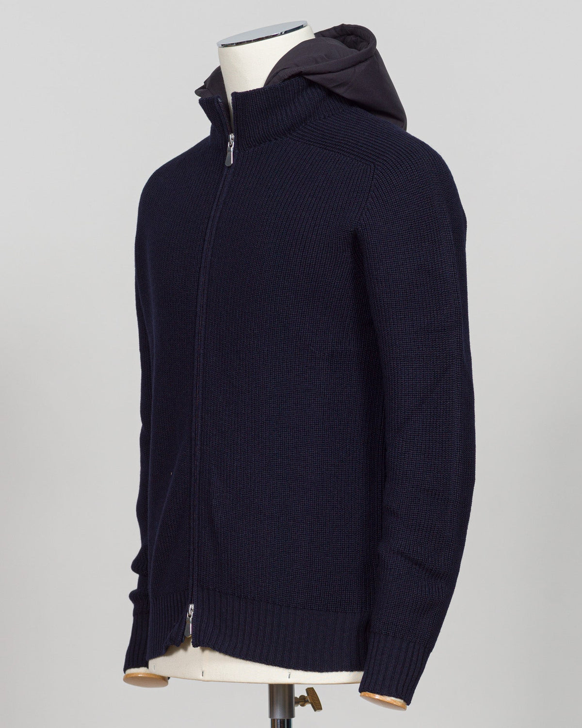 A dark navy blue ribbed knit zip-up hoodie with a hood, displayed on a mannequin torso against a light gray background. Water-repellent merino wool hoodie in navy. Engineered for layering and everyday wear, this Gran Sasso piece combines breathable warmth with practical weather resistance. Perfect for transitional seasons and active lifestyles. Gran Sasso Rain Wool Hoodie / Navy