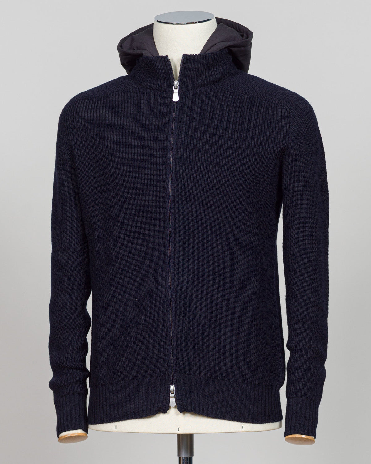 A dark navy blue ribbed knit zip-up hoodie with a hood, displayed on a mannequin torso against a light gray background. Water-repellent merino wool hoodie in navy. Engineered for layering and everyday wear, this Gran Sasso piece combines breathable warmth with practical weather resistance. Perfect for transitional seasons and active lifestyles. Gran Sasso Rain Wool Hoodie / Navy