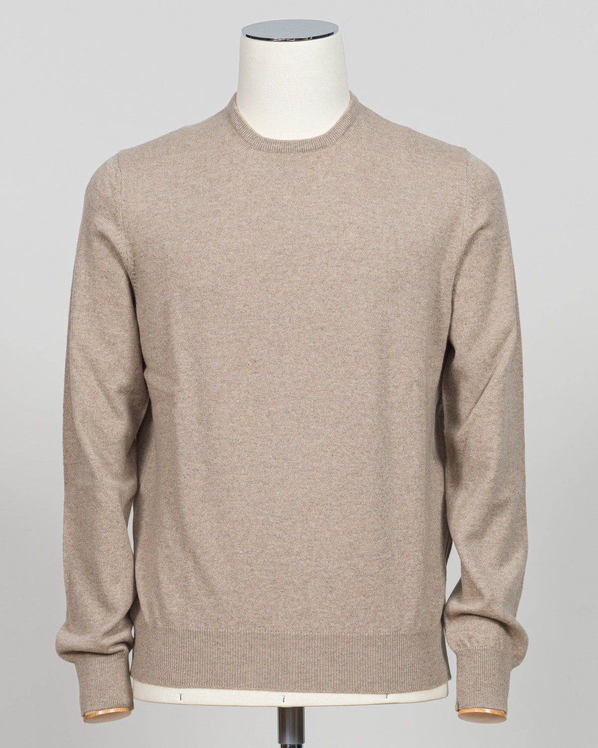 A light beige crewneck knit sweater displayed on a white mannequin torso against a neutral light gray background.  Gran Sasso's timeless cashmere crew neck in soft beige epitomizes understated luxury. Crafted from 100% pure cashmere with a vintage-washed finish that develops character with wear, this Italian-made essential features a relaxed fashion fit, ribbed detailing at the hem and cuffs, and a refined crew neckline. An investment piece that anchors any wardrobe. Gran Sasso Cashmere Crew Neck / Beige