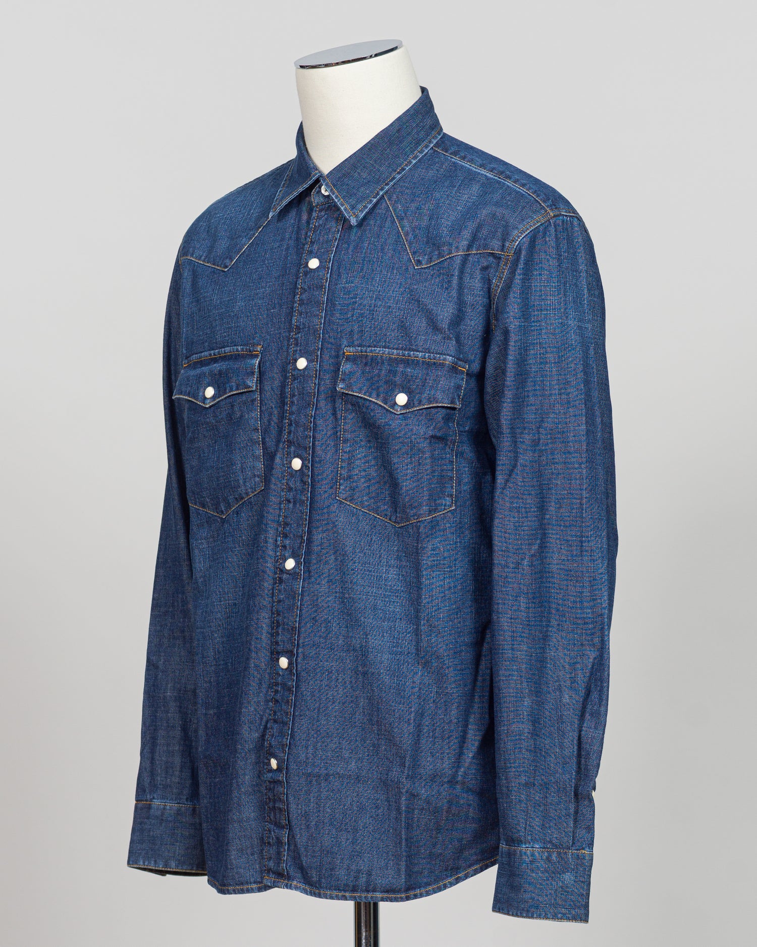 Crafted from premium Tela Genova fabric, this Western shirt delivers understated sophistication in a faded blue that transitions beautifully across seasons. The structured weave and refined tailoring define clean lines, while pearl snaps and a relaxed collar offer versatile styling—equally at home layered under a blazer or worn open as a lightweight layer. Perfect for the discerning dresser who values quality construction and timeless design.