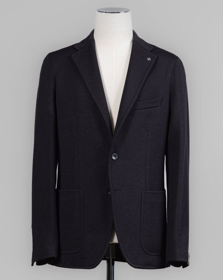 Tagliatore's refined jersey jacket combines Italian craftsmanship with modern ease. The lightweight knit construction offers comfort and movement, while the structured silhouette maintains a polished appearance. Perfect for layering or wearing solo, this black essential transitions seamlessly from office to weekend. Tagliatore Jersey Jacket / Black