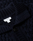 Knitted with a chunky, open cable stitch, this merino wool cardigan jacket is a contemporary take on a traditional Sunspel classic. Made in England, it has a funnel neck collar and horn buttons. Warm, and comfortable it is the ideal transeasonal outer layer. Made in England 100% Merino Wool Cool hand wash Do not tumble dry Dry cleanable Sunspel Cable Knit Cardigan Jacket / Navy