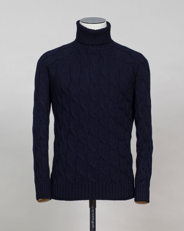 Gran Sasso cable knit roll neck made of special 3-ply Air Wool quality. The special feature of this garment is the yarn that holds microscopic air bubbles between the fibers, making it at the same time warm and light.  Art. 13117/22622 Col. 598 Navy 100% Wool Made in Italy