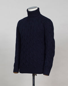 Gran Sasso cable knit roll neck made of special 3-ply Air Wool quality. The special feature of this garment is the yarn that holds microscopic air bubbles between the fibers, making it at the same time warm and light.  Art. 13117/22622 Col. 598 Navy 100% Wool Made in Italy