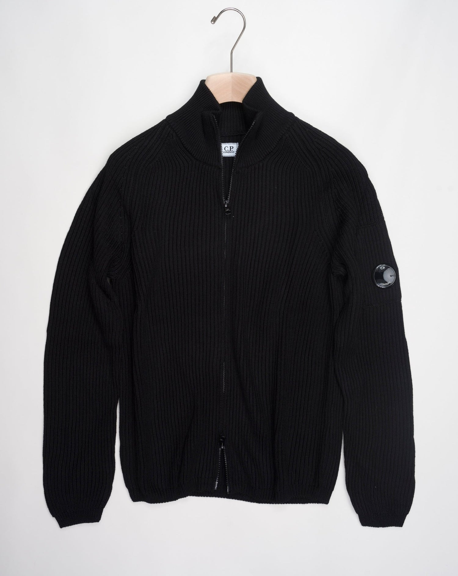 Art. 15CMKN228A 006595A Col. 999 Black Full two way zip C.P. Company lens detail on left sleeve Heavy ribbed  Composition: 55% wool 45% pl C.P. Company Re-Wool Zipped Knit / Black