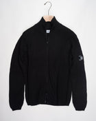 Art. 15CMKN228A 006595A Col. 999 Black Full two way zip C.P. Company lens detail on left sleeve Heavy ribbed  Composition: 55% wool 45% pl C.P. Company Re-Wool Zipped Knit / Black