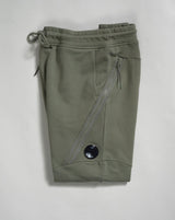 Sweatpants with an adjustable drawstring waistband and tapered legs. The sweatpants also feature slanted hand pockets and a C.P. Company Lens detail on the left leg. Crafted in diagonal raised fleece, a midweight loopback cotton option that combines absolute comfort with a substantial and hard-wearing feel.  14CMSP084A005086W Col 648 Bronze Green Adjustable drawstring waistband Slanted hand pockets Angular thigh zip pockets Lens detail Tapered leg