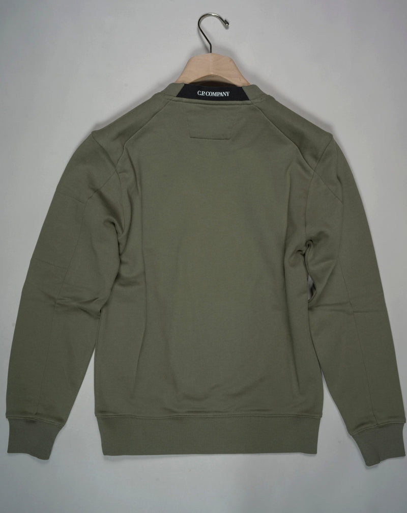 Crewneck sweatshirt featuring the C.P. Company Lens on the sleeve pocket. Manufactured in our diagonal raised fleece, a midweight loopback cotton option that combines absolute comfort with a substantial and hard-wearing feel. Art. SP084A 5086W Col. 648 Bronce Green Ribbed Cuffs, Hem and Neck Lens Detail Sleeve Pocket Logo Detail Back Collar