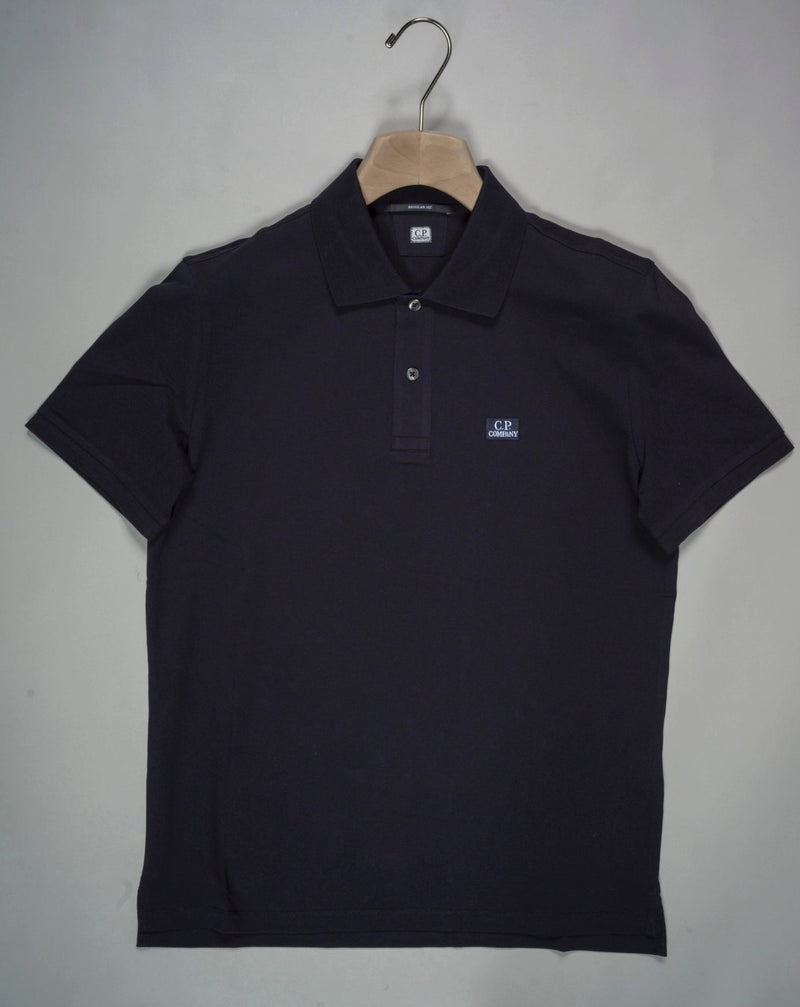 Regular fit polo shirt cut in a short sleeve construction with a two button placket, a classic collar, and the C.P. Company logo on the chest. Made in a fine 24/1 cotton pique, and resist dyed for a varied, tonal finish. Art. PL094A5263W 005263W Col. 888 Total Eclipse Classic collar Two button placket Logo detail Short sleeves Resist dyed Regular fit 