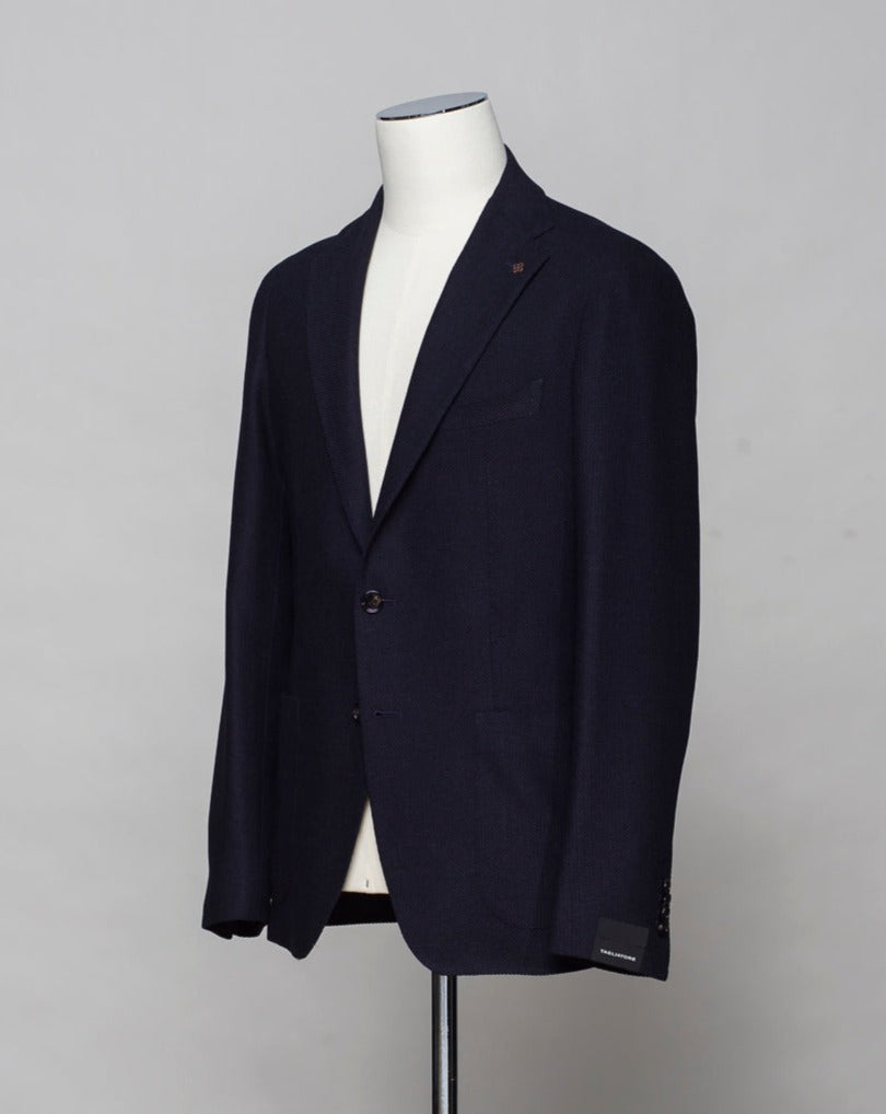 Hopsack jersey jacket from Sauma 20 anniversary capsule collection. Crafted in Martina Franca, Italy by Tagliatore. Natural stretch hopsack jersey jacket. Composition: 72% Silk 28% Virgin wool. Article: 440038 U. Modello: Sauma 20 / Monte Carlo / 1SMC22K. Color: Navy / B3085. Unconstructed. Unlined. 2 Buttons. Notch lapel. Patch pockets. Side vents. Made in Martina Franca, Italy