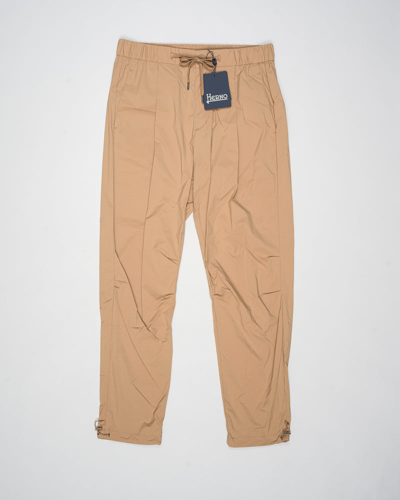 Trousers made of 20 denier stretch nylon whose weft and warp create a lightweight, matt and stretch fabric.
Comfortable to wear thanks to the drawstring that can be adapted to the desired fit, the style has a casual yet sophisticated feel that updates your everyday wardrobe.


Regular fit

Elastic with drawstring waist

Pleats at the front

Zip and button fastening

Slanted pockets

Patch pockets on the back

Drawstring at the ankles
Article: PT000041U 12431SZ
Color: Camel / 2157