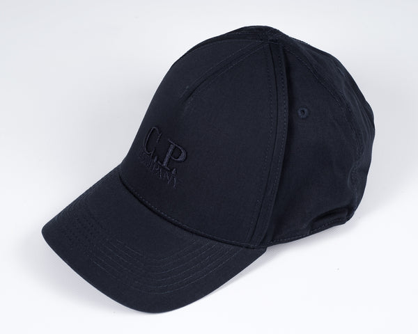 Men´s cotton gabardine cap with embroidered C.P. -logo in front, adjustable strap in the back and tone on tone stitchings  and detailing. A classic six panel structure.  Crafted in a classic six panel style, this men's cap features a curved brim, tonal- Curved Brim Embroidered Logo Stitched Detailing Six Panel Construction Adjustable Strap Mod. MAC091A00 5279A Col. 888 / Total eclipse