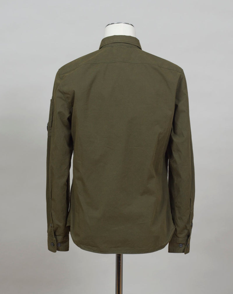 A buttoned shirt featuring a classic collar, secure pockets at the chest, and a discreet sleeve compartment finished with the C.P. Company Lens detail.  Classic Collar Full Button Fastening Secure Chest Pockets Lens Detail Sleeve Pocket Col. 683 / Ivy Green 100% Cotton Art. 12CMSH088A 002824G