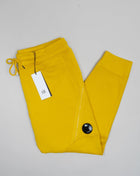 C.P. Company's diagonal raised fleece is a mid-weight option that's woven from a soft loopback cotton, for premium comfort with a durable, rugged feel.  Side slip pockets Lens detail Cargo Pocket on left side Tapered fit Adjustable drawstring waist Art. 12CMSP084A 005086W Col 239 / Nugget Gold / Yellow 100% cotton