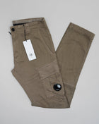 Button Fastening Belt Loops Slanted Hand Pockets Twin Cargo Pockets Back Pockets Lens Detail Garment Dyed 98% Cotton 2% Elastane Art. 12CMPA056A005694G Col. 322 Seneca Rock / Khaki Green Wash max 30°C - Mild process Functional men's cargo pants crafted with a fitted leg, featuring reinforced belt loops, slanted hand pockets, and secure cargo compartments at each leg. Finished with the C.P. Company Lens detail
