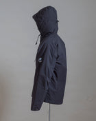 C.P. Company Pro-Tek Hooded Jacket that combines the weight and comfort of a sweatshirt with the protective functions of an outer layer. Water resistant coating on the upper layer of the jacket. Art. 13CMOW025A 004117A Col. 999 / Black Zippered pocket  Pocket with C.P. Company Lens on the left arm Adjustable hood and hem Water resistant