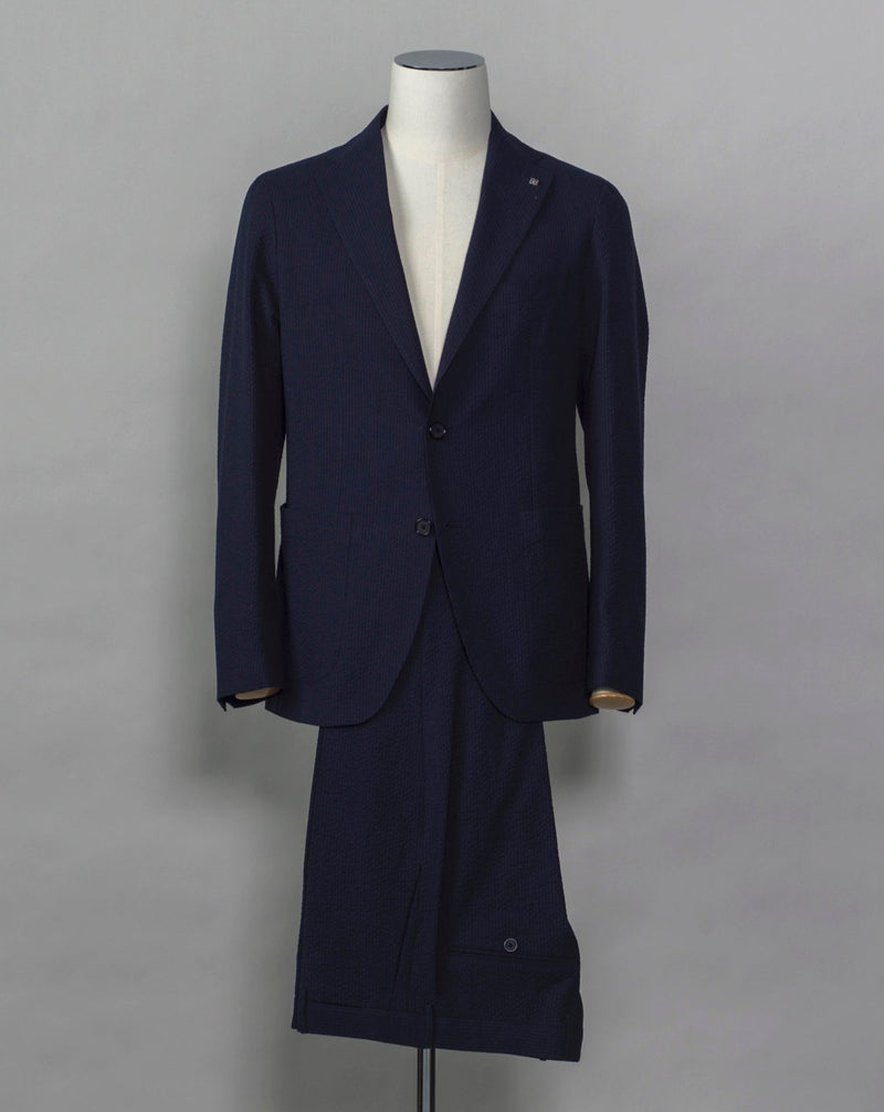 Tagliatore Seersucker summer suit.  Unlined jacket and unconstructed shoulders combined with this iconic summer fabric are guaranteed to keep you comfortable even on the hottest summer parties.  Composition: 96% Cotton 3% Elastan Bistretch 1% Polyamide (Nylon) Modello: 2SMC22K01 Color: Navy / B1185 Unconstructed Unlined 2 Buttons Notch lapel Patch pockets Side vents Flat front Belt loops Made in Martina Franca, Italy