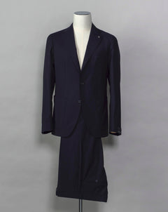 Tagliatore single breasted suit with unconstructed shoulder and unlined inside structure. Relaxed and comfortable, but at the same time look remains very smart and sharp. Composition: 99% Virgin Wool Super 110's 1% Elastan Stretch Modello: 2SMC22K01 Color: Navy / B5092 Unconstructed Unlined 2 Buttons Notch lapel Patch pockets Side vents Flat front Belt loops Made in Martina Franca, Italy