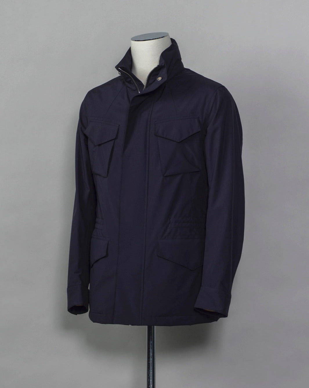 Montecore waterproof field jacket. Four pockets in front and adjustable waistband. Adjustable hood that can be folded inside the collar. So all the classical elements of a proper field jacket plus the added value of a waterproof and breathable technical  material. Four pockets in front Adjustable waist band Adjustable hood inside the collar Waterproof Breathable Taped seams  79% Polyester 21% Polyurethane Art. S04MUCT603 Col. 89 / Navy